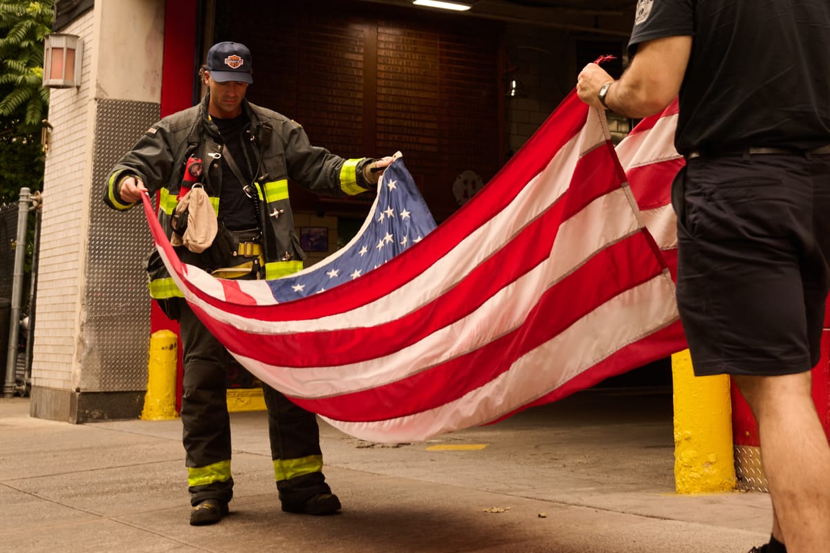 Firefighters unfurl the American flag at the FDNY Engine 28/Ladder 11 firestation (Vincent Guglielmo)